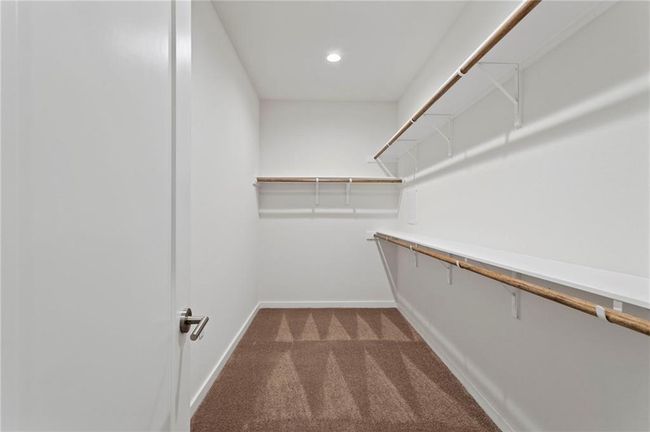 Walk in closet featuring dark carpet | Image 18
