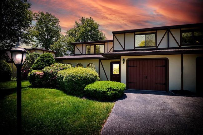English style home with stucco siding, a front lawn, driveway, and a garage | Image 37