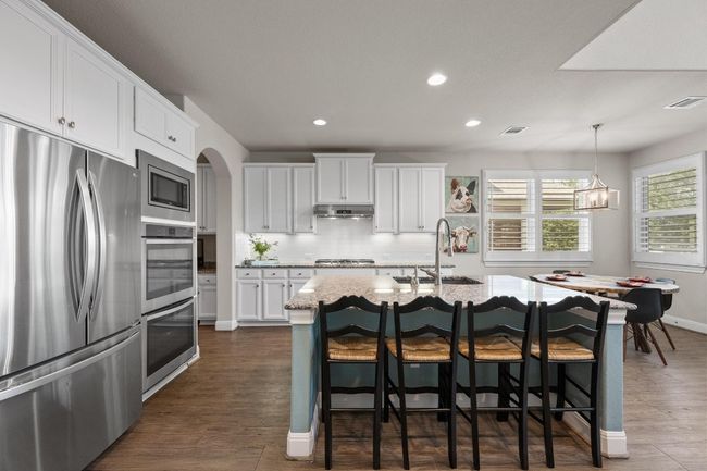 Kitchen with stainless steel appliances, recessed lighting, backsplash, white cabinets, large pantry and dark wood-style floors | Image 10