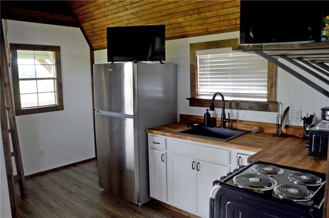 Kitchen with butcher block countertops, freestanding refrigerator, a sink, black range with electric stovetop, and wood ceiling | Image 19