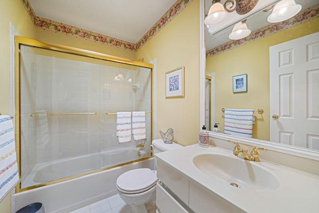 Bathroom featuring vanity, bath / shower combo with glass door, and tile patterned flooring | Image 11