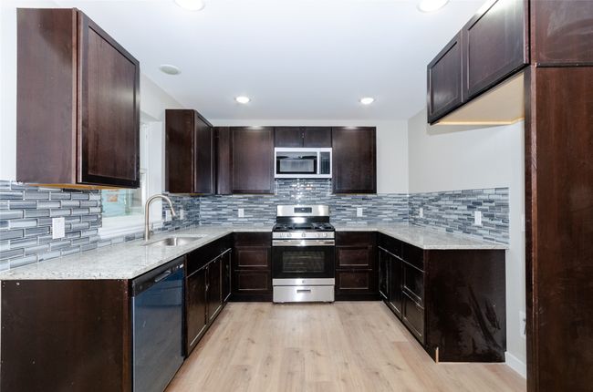 Kitchen with a sink, light stone countertops, light wood-type flooring, and stainless steel appliances | Image 6
