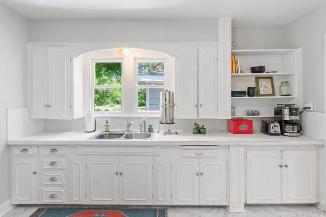 Kitchen has original wood cabinetry, arched window overlooking the huge lot and separate coffee area. | Image 14