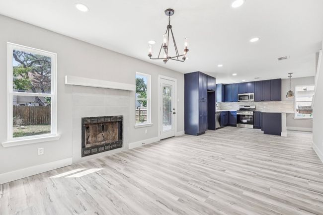 Unfurnished living room with healthy amount of natural light, a chandelier, light wood-type flooring, baseboards, and recessed lighting | Image 10
