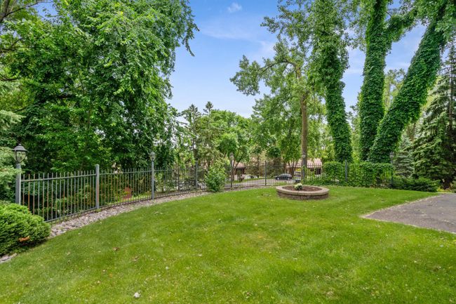 Beautifully landscaped front yard with wrought iron fencing, mature trees, and a charming circular flower bed offering curb appeal and privacy. | Image 32