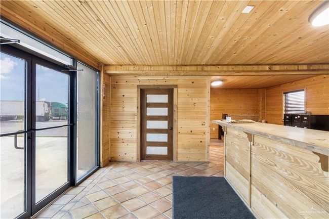 Kitchen featuring wood ceiling, wooden walls, light tile patterned flooring, and light countertops | Image 6