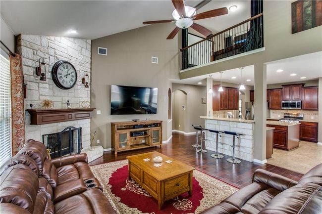 Living area featuring ceiling fan, high vaulted ceiling, a fireplace, and wood finished floors | Image 8