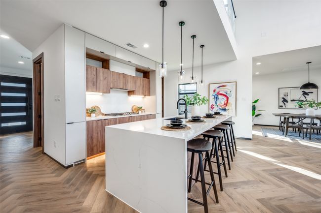 Kitchen with modern cabinets, brown cabinets, light countertops, a kitchen bar, and recessed lighting | Image 8