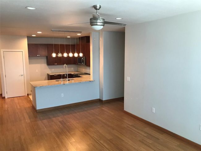 Kitchen with a sink, stainless steel microwave, a peninsula, a ceiling fan, and light wood-type flooring | Image 8