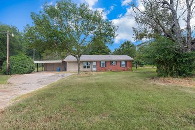 Ranch-style house featuring a carport and a front lawn | Image 1