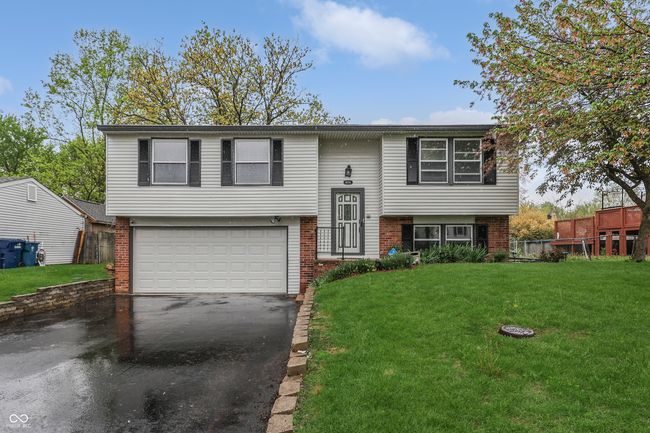 bi-level home with a garage, brick siding, aphalt driveway, and a front yard | Image 4