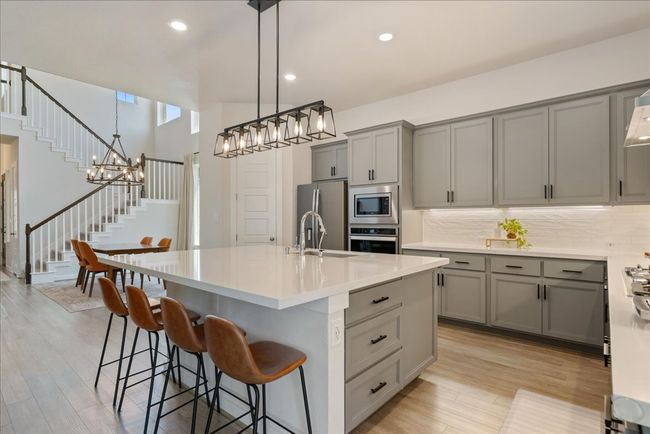 Kitchen featuring light countertops, gray cabinetry, appliances with stainless steel finishes, light wood finished floors, and a sink | Image 10