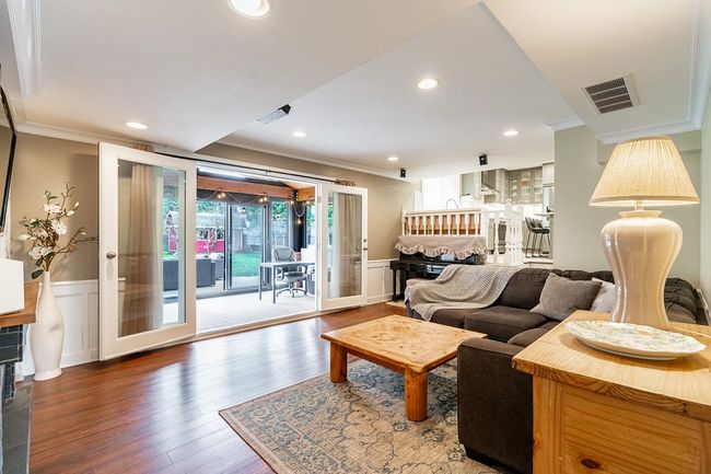 Living room featuring wainscoting, ornamental molding, wood finished floors, and visible vents | Image 16