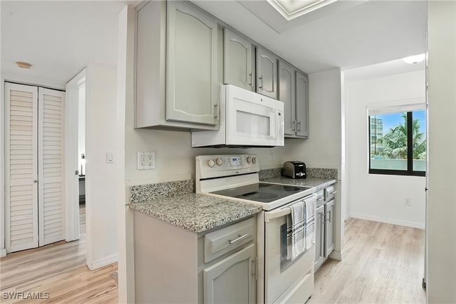 Kitchen featuring white appliances, gray cabinets, light wood finished floors, and light stone countertops | Image 15