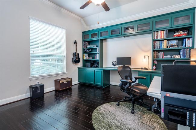 Custom built-ins installed with trendy color. Ceiling fan for added comfort while working. Wood flooring. | Image 7