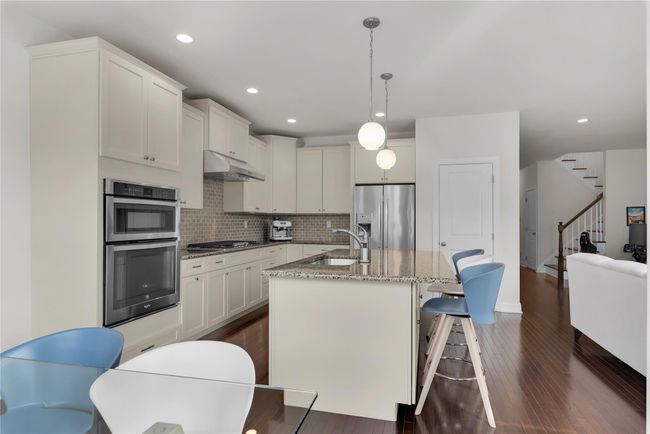 Kitchen with double oven, hanging light fixtures, white cabinetry, stone countertops | Image 5