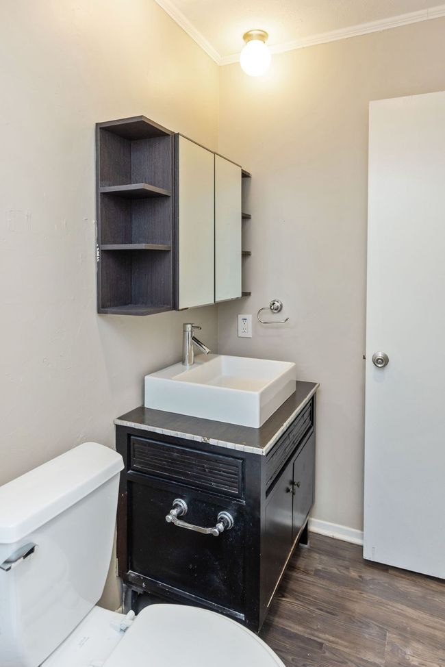 Half bath with toilet, vanity, crown molding, and wood finished floors | Image 25