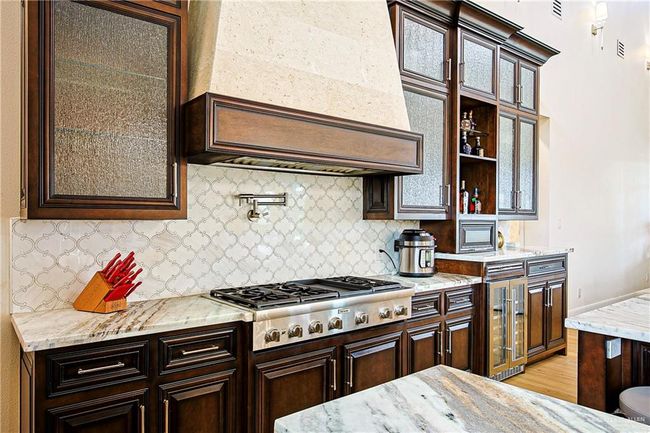 Kitchen featuring beverage cooler, 6 burner gas stove with a flat top, maple custom cabinets, and backsplash | Image 19