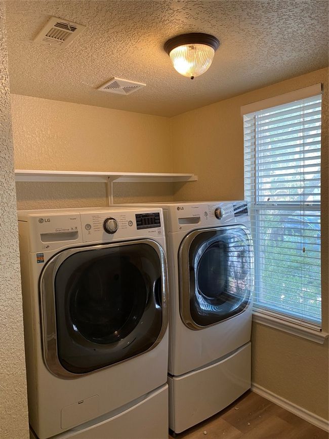 Laundry area with separate washer and dryer, wood finished floors, a textured ceiling, a textured wall, and baseboards | Image 15