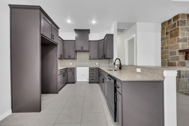 Kitchen with sink, gray cabinetry, kitchen peninsula, black dishwasher, and decorative backsplash | Image 14