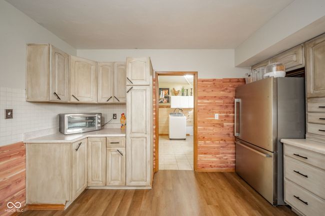 kitchen featuring washer / clothes dryer, a toaster, light countertops, freestanding refrigerator, and light wood finished floors | Image 31