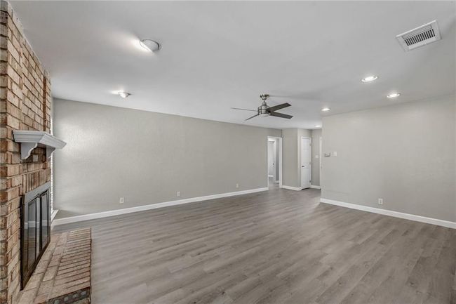 Unfurnished living room featuring a brick fireplace, a ceiling fan, recessed lighting, wood finished floors, and baseboards | Image 4