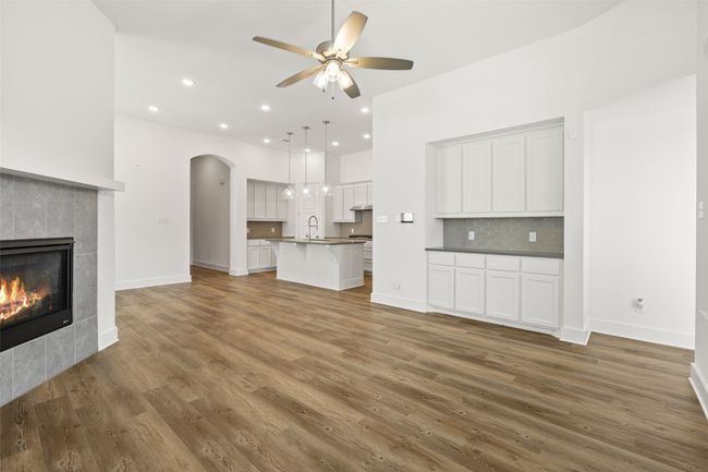 Unfurnished living room featuring a sink, a ceiling fan, a fireplace, wood finished floors, and baseboards | Image 6