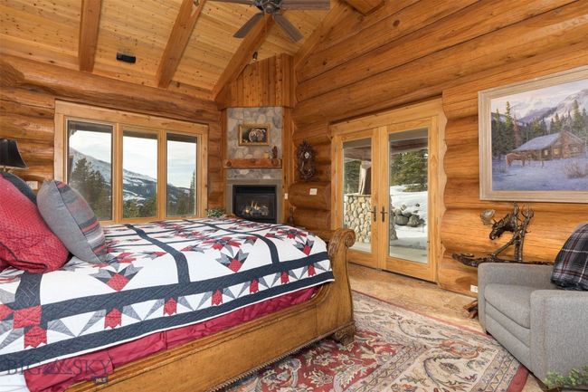 Main level primary bedroom featuring beamed ceiling with fan, fireplace and access to exterior hot tub patio. | Image 17