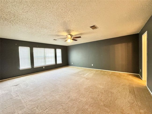 Empty room with light carpet, ceiling fan, and a textured ceiling | Image 13