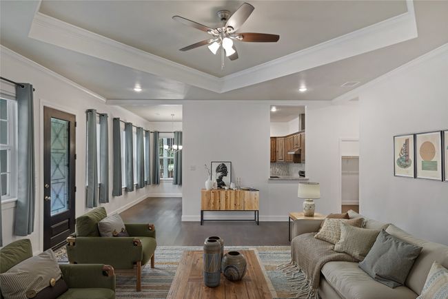 Living room featuring a ceiling fan, dark wood-style floors, a chandelier, crown molding, and a raised ceiling | Image 5