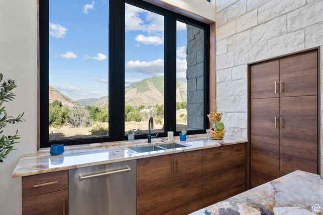 Kitchen featuring stainless steel dishwasher, light stone counters, and healthy amount of natural light | Image 28