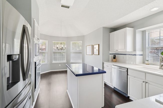 Kitchen with stainless steel appliances, a sink, dark wood-type flooring, a chandelier, and decorative backsplash | Image 11