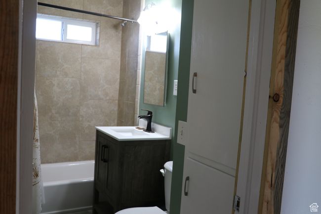 Bathroom with toilet, vanity, and shower / bathtub combination with curtain | Image 9
