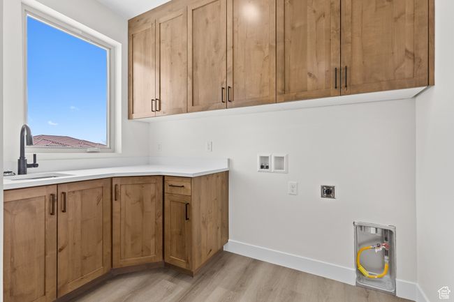 Washroom featuring a sink, washer hookup, hookup for an electric dryer, light wood-style floors, and cabinet space | Image 23