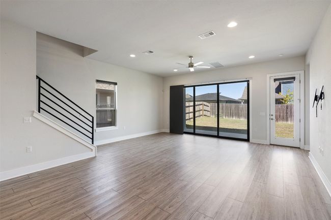 Unfurnished living room featuring wood finished floors, ceiling fan, stairway, and recessed lighting | Image 7