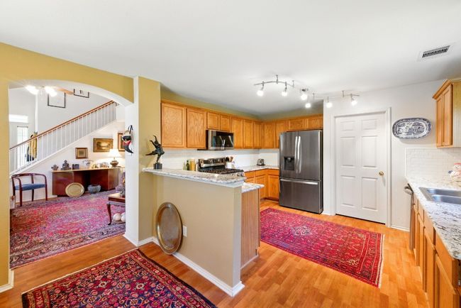 Kitchen featuring appliances with stainless steel finishes, light wood-style flooring, a sink, decorative backsplash, and a peninsula | Image 11