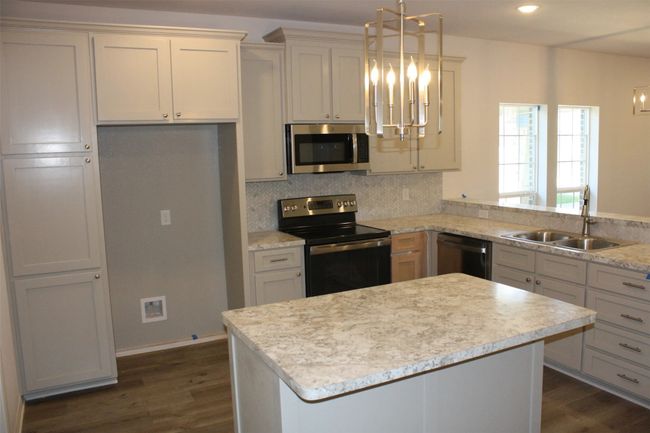 Kitchen with a chandelier, stainless steel appliances, dark wood finished floors, light countertops, and recessed lighting | Image 5