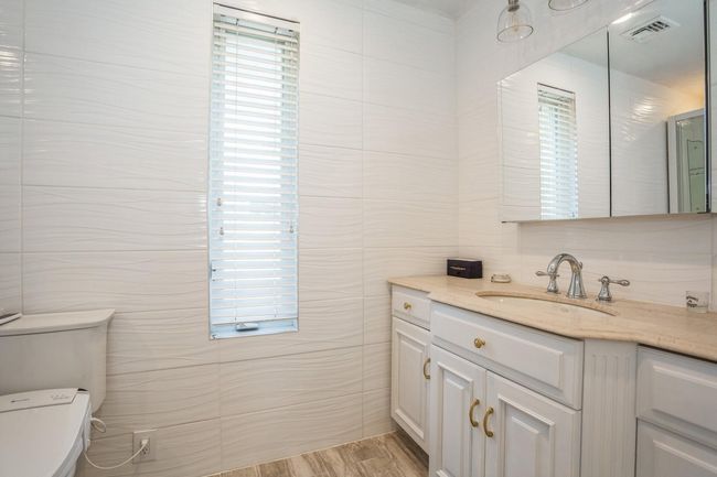 Bathroom featuring tile walls, visible vents, plenty of natural light, toilet, and vanity | Image 8