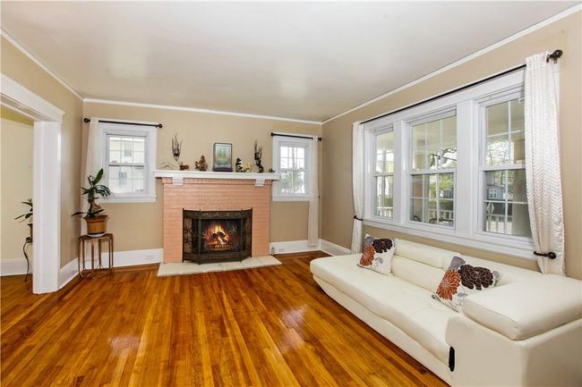 Formal living room with fireplace and hardwood floors, opens to the dining room. | Image 8