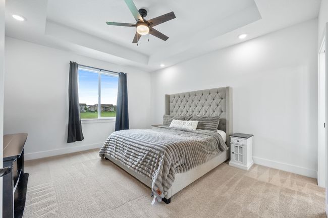 Bedroom featuring recessed lighting, light carpet, baseboards, a tray ceiling, and ceiling fan | Image 15