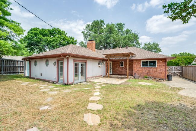 Back of property with french doors, a chimney, a patio, and roof with shingles | Image 38