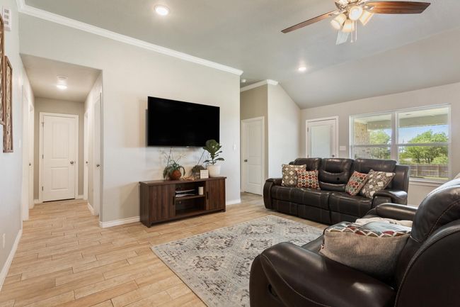 Living room with ceiling fan, light wood finished floors, crown molding, recessed lighting, and vaulted ceiling | Image 9