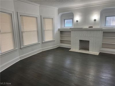 Unfurnished living room with dark hardwood / wood-style floors, ornamental molding, a textured ceiling, and a brick fireplace | Image 3