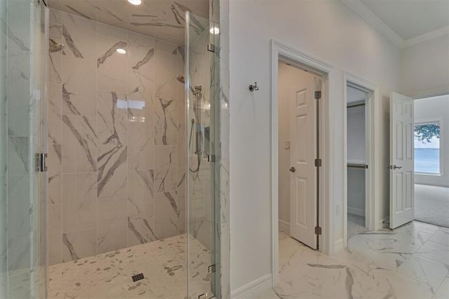 The oversized shower, measuring 48" x 60", features a seamless glass surround and an adjustable showerhead, making it ideal for ADA accessibility. Thoughtfully designed with future needs in mind, the shower and adjacent toilet area include reinforced blocking behind the sheetrock at 36" above the floor, ready for grab bar installation if desired. | Image 25