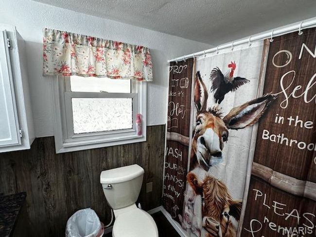 Bathroom featuring wood walls, a textured ceiling, and toilet | Image 5