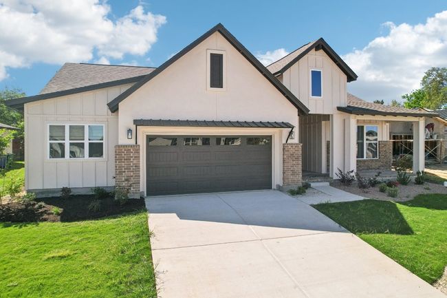 Modern farmhouse with board and batten siding, a front yard, a shingled roof, and concrete driveway | Image 4