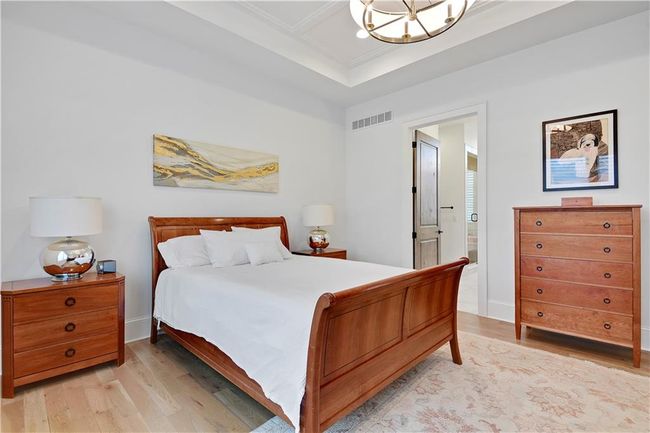 Bedroom featuring a notable chandelier, light wood finished floors, ensuite bathroom, and visible vents | Image 31