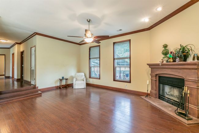 Unfurnished living room with visible vents, a glass covered fireplace, crown molding, and wood finished floors | Image 4