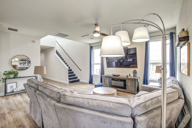 Living room with wood finished floors, stairs, and ceiling fan | Image 7