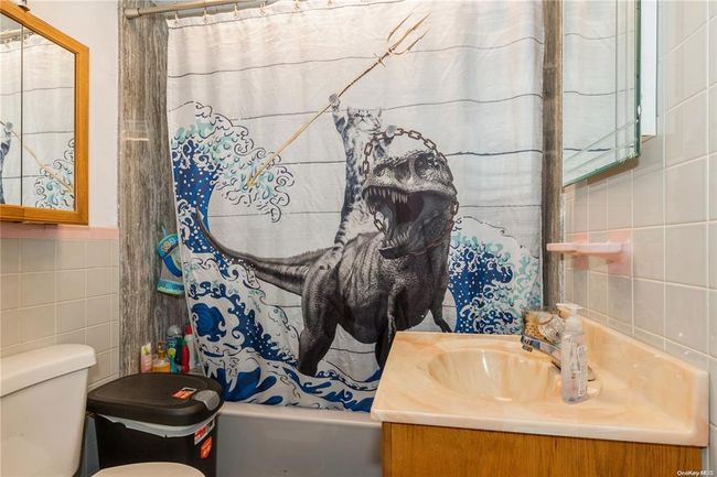 Bathroom with shower / tub combo, toilet, vanity, and tile walls | Image 12